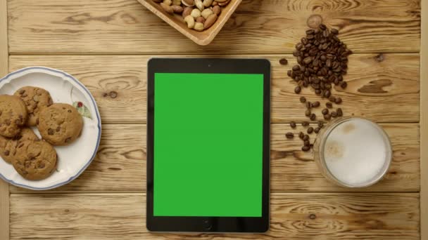 Timelapse zonsondergang met groene tablet, koffiebeker, koffiebonen, koekjes en noten - Video