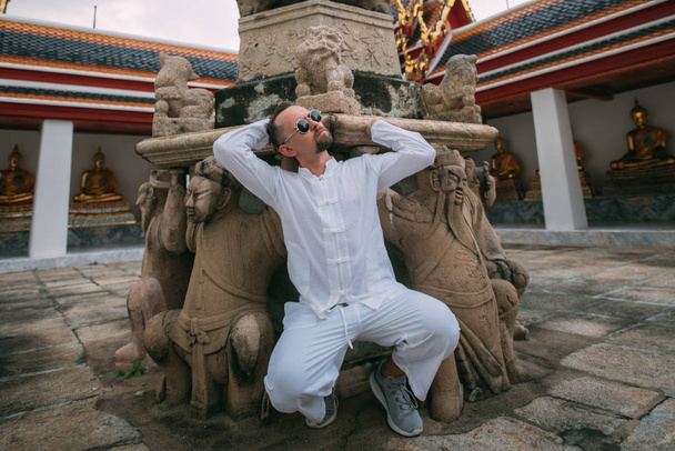 Ένας άντρας διασκεδάζει ποζάροντας σε ένα βουδιστικό παλάτι.. - Φωτογραφία, εικόνα