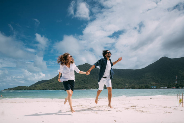 A pair of lovers have fun running around on a tropical beach. - 写真・画像