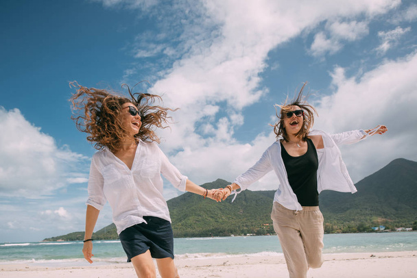 Влюбленные девушки веселятся, бегая по тропическому пляжу.
 - Фото, изображение