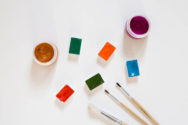Vesivärimaaleja eri värejä ojia valkoisessa laatikossa ja harjat puinen kahvat valkoisella pohjalla. Piirustus ja mestariluokat taidekouluun
 - Valokuva, kuva