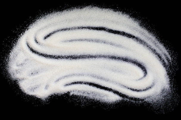 A finomított szemcsés cukor textúrája sötét alapon, a granulált cukor absztrakt szétszóródása. Texturált hatás kézzel húzott hullám egy halom édes cukor - Fotó, kép