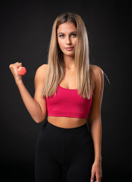 junge Sport blonde Frau macht Gewichtheben über isolierten schwarzen Hintergrund - Foto, Bild