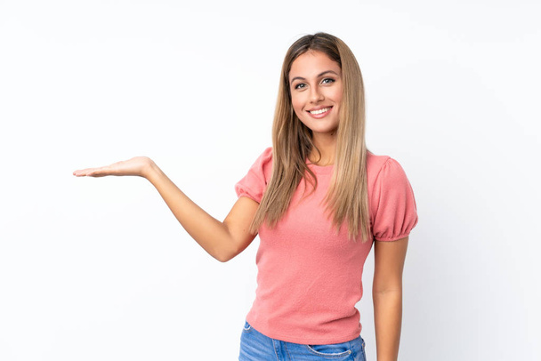 Jonge blonde vrouw over geïsoleerde witte achtergrond houden copyspace imaginaire op de palm om een advertentie in te voegen - Foto, afbeelding