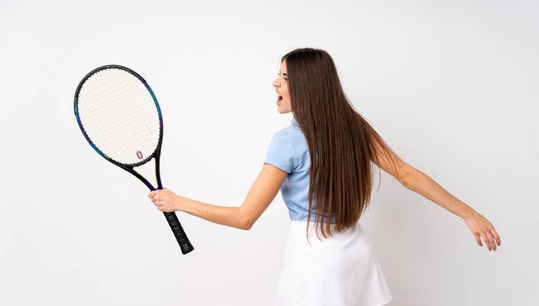 Молода дівчина над ізольованою білою стіною грає в теніс і святкує перемогу
 - Фото, зображення