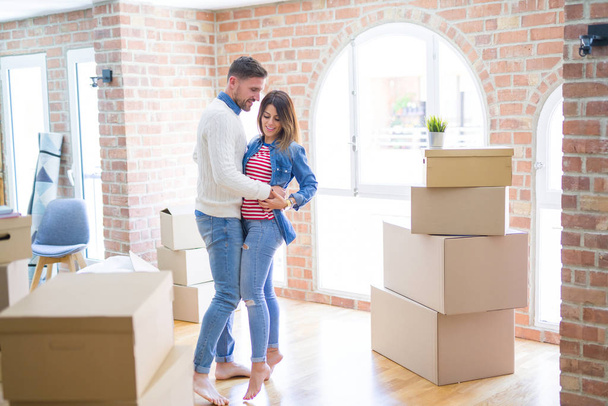 Joven hermosa pareja bailando en un nuevo hogar alrededor de cajas de cartón
 - Foto, imagen
