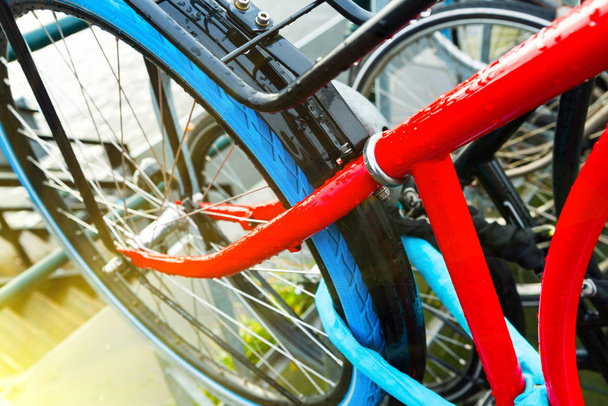 Close up de uma bicicleta vermelha moderna com pneus azuis estacionados nas ruas de Amsterdã pela manhã
 - Foto, Imagem