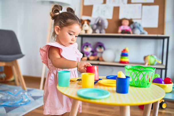 Jovem linda criança brincando com talheres e brinquedos de comida na mesa no kindergaten
 - Foto, Imagem