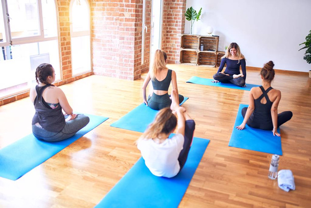 Jovem grupo bonito de esportistas praticando ioga. Treinador de ensino esticar para mulheres desportivas no ginásio
 - Foto, Imagem