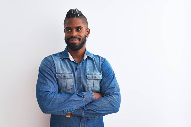 African american man with braids wearing denim shirt over isolated white background smiling looking to the side and staring away thinking. - Фото, изображение