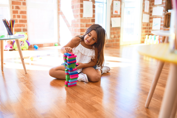 Чарівний малюк сидить на підлозі. Гра з дерев'яними будівельними блоками в дитячому саду
 - Фото, зображення