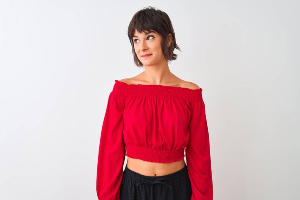 Νεαρή όμορφη γυναίκα που φοράει κόκκινο καλοκαιρινό t-shirt στέκεται πάνω από απομονωμένο λευκό φόντο χαμογελώντας κοιτάζοντας στο πλάι και κοιτάζοντας μακριά σκέψης. - Φωτογραφία, εικόνα