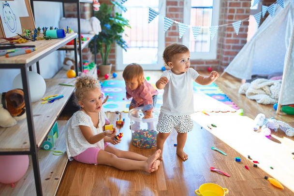 Schattige peuters spelen rond veel speelgoed op de kleuterschool - Foto, afbeelding
