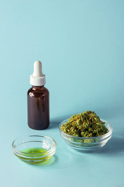 Glass Bottle and Dish of CBD or THC Oil with Hemp or Cannabis Buds on Aqua Blue Background - Zdjęcie, obraz