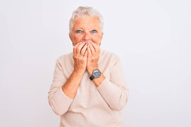 Старшая седовласая женщина в свитере в водолазке стоит на изолированном белом фоне смеясь и смущенно хихикая, прикрывая рот руками, сплетнями и скандалом
 - Фото, изображение