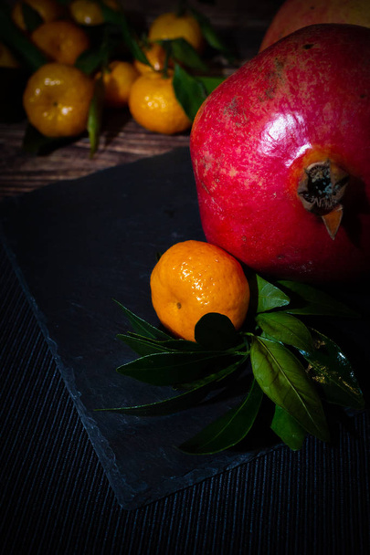 Still life of pomegranates and tangerines in the dark key. Composition of ingredients (fruits) for  making fresh juice. - Foto, afbeelding
