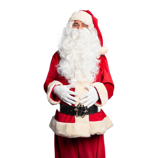 Красивый мужчина средних лет в костюме Санта-Клауса и с бородой стоя улыбаясь и громко смеясь, потому что смешная сумасшедшая шутка с руками на теле
. - Фото, изображение