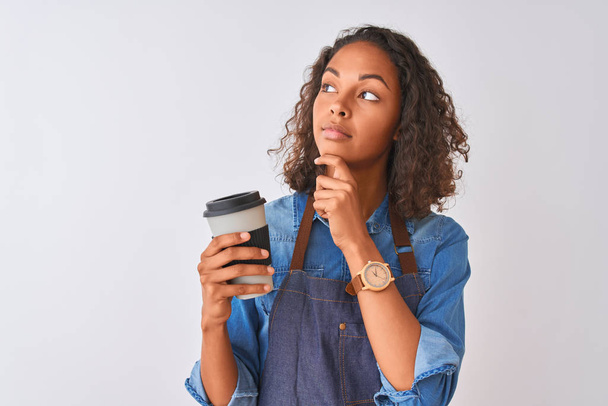 Young brazilian barista woman drinking take away coffee over isolated grey background serious face thinking about question, very confused idea - Zdjęcie, obraz