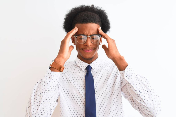 junge afrikanisch-amerikanische Geschäftsmann trägt Krawatte und Brille über isoliertem weißen Hintergrund mit der Hand auf dem Kopf für Schmerzen im Kopf wegen Stress. Migräne. - Foto, Bild