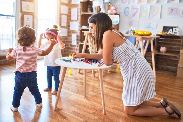 Young beautiful teacher and toddlers playing at kindergarten - Photo, Image