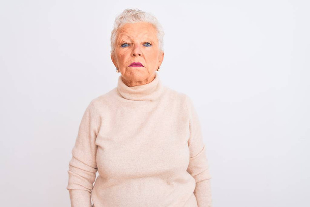 Starší šedovlasá žena v rolákovém svetru, stojící nad osamělým bílým pozadím Uvolněná s vážným výrazem ve tváři. Jednoduchý a přirozený pohled do kamery. - Fotografie, Obrázek