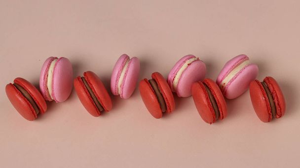 Sabrosas galletas dulces, macarrones rojos y rosados sobre fondo rosa, Vista superior, orientación horizontal
 - Foto, imagen