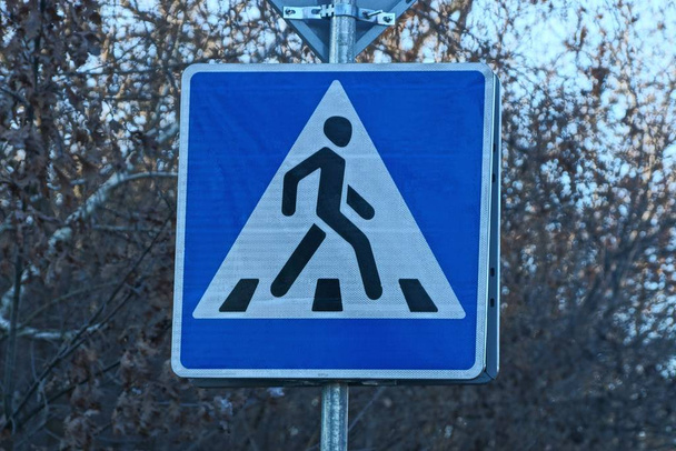 дорожный знак пешеходный переход на фоне серых ветвей
 - Фото, изображение
