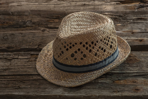 A straw hat is on an old wooden background. - Fotografie, Obrázek