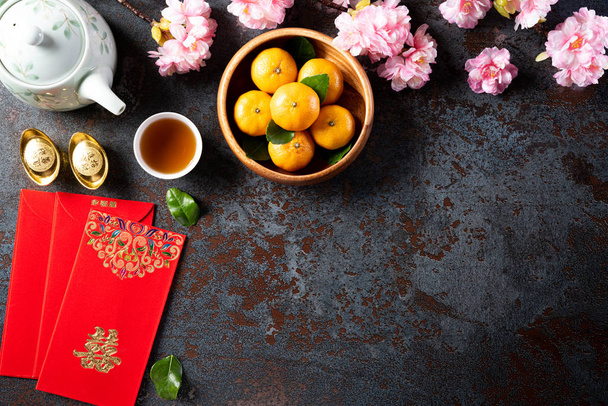 Chiński Nowy Rok dekoracje festiwalowe pow lub czerwony pakiet, pomarańczowe i złote sztabki lub złoty guzek na czarnym tle tekstury kamienia. Chińskie znaki Fu oznacza szczęście, bogactwo, przepływ pieniędzy. - Zdjęcie, obraz
