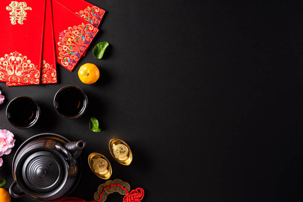 Chinese nieuwjaar festival decoraties pow of rood pakket, oranje en gouden ingots of gouden brok op een zwarte achtergrond. Chinese karakters Fu betekent geluk, rijkdom, geldstroom. - Foto, afbeelding