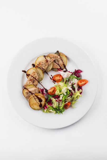 gebakken aardappel- en vleesschijfjes met salade op witte plaat  - Foto, afbeelding