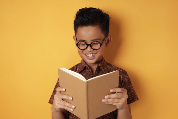 Smart Asian Boy Smiling While Reading Book - Фото, изображение