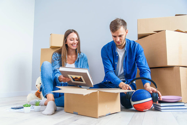 Young couple unpacking things after moving into new house - Фото, изображение