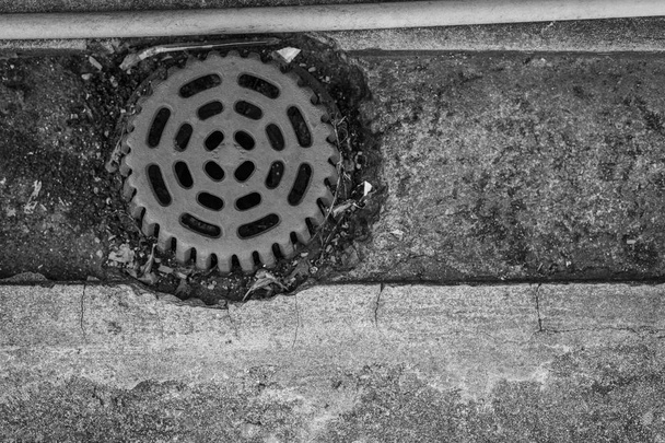 Стара каналізаційна шапка на бетонній підлозі
 - Фото, зображення