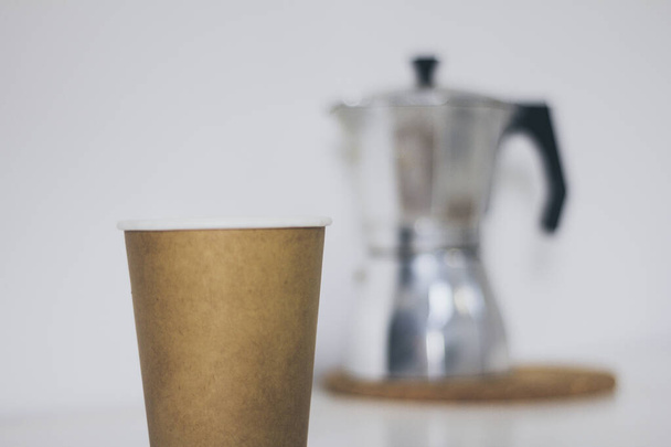 Переработка коричневой чашки и серебристый кофе машина на белый стол
 - Фото, изображение