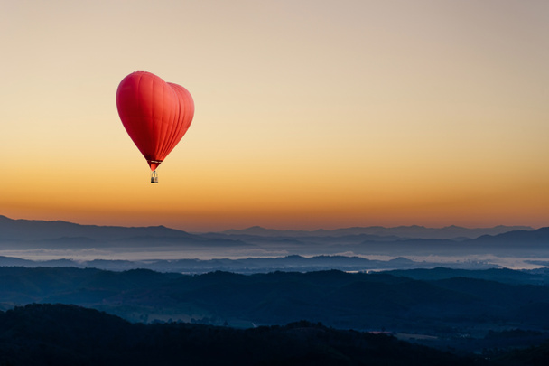 Globo de aire caliente rojo en forma de corazón volando
  - Foto, Imagen