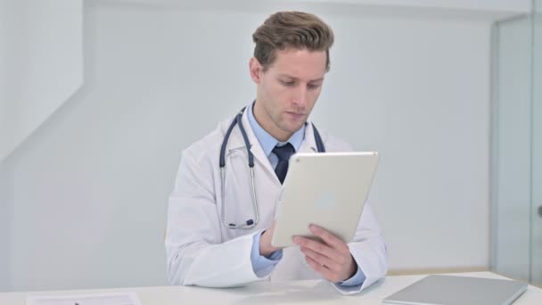 Tvrdě pracující mladý muž lékař pomocí tabletu v moderní kanceláři - Záběry, video