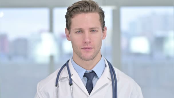 Portret uśmiechniętego młodego lekarza patrzącego w kamerę - Materiał filmowy, wideo