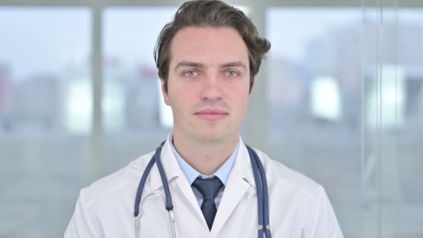 Portret uśmiechniętego młodego lekarza patrzącego w kamerę - Materiał filmowy, wideo