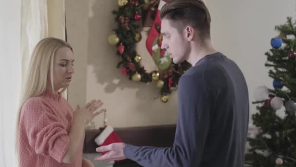 Handsome Caucasian man trying to take wifes hand, nervous woman yelling at husband. Couple quarrelling on Christmas eve. Problems, misunderstanding, divorce. - Materiał filmowy, wideo