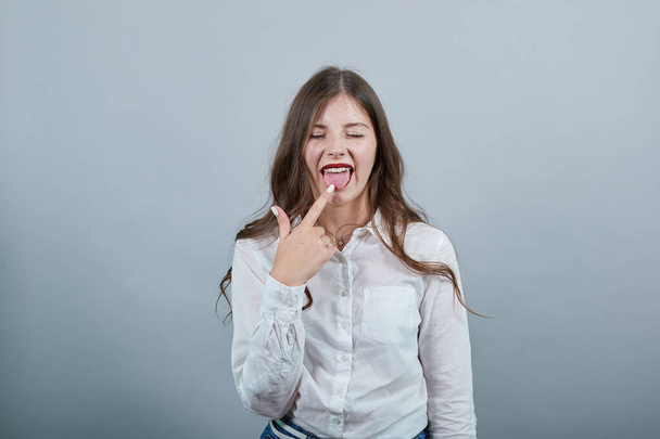 Femme déçue en chemise blanche gardant doigt sur langue, l'air confus
 - Photo, image