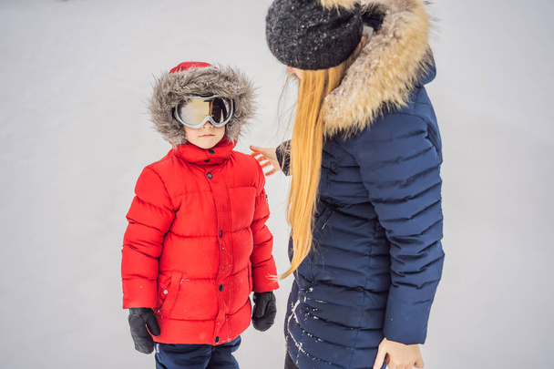 Mom puts on ski glasses for her son - Foto, afbeelding
