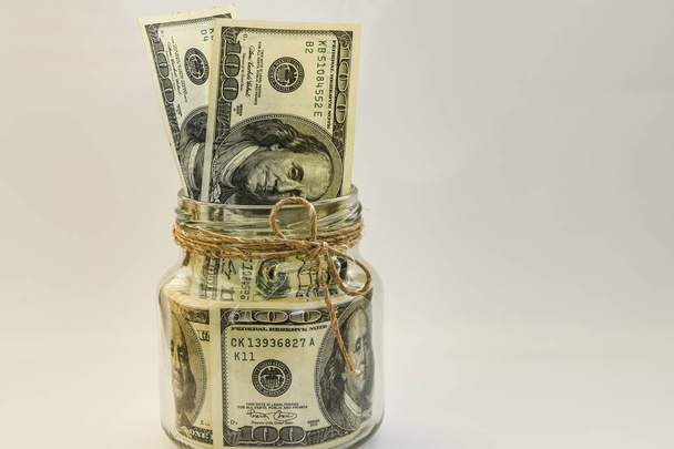 hundert amerikanische Dollar im Glas auf weißem Hintergrund mit Kopierraum, Ersparnis, - Foto, Bild