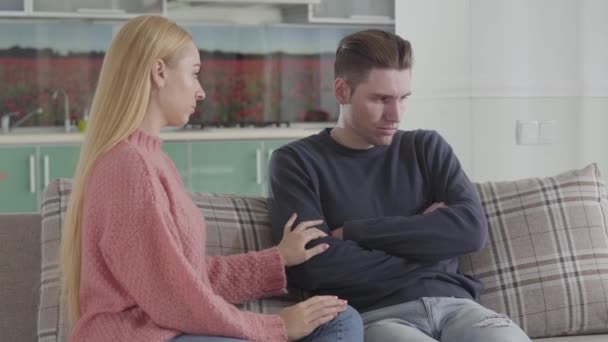 Sad Caucasian woman trying to kiss husband, man turning away. Wife calming down upset spouse at home. Depression, conflict, relationship problems. - Materiał filmowy, wideo