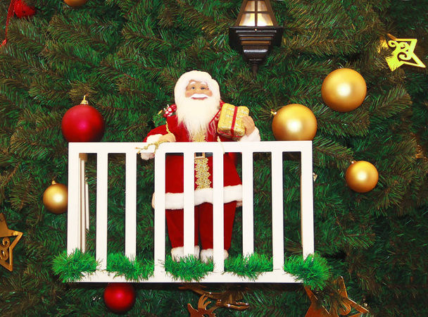 Santa Claus with a gift on the background of a green Christmas tree and toys - Foto, Bild