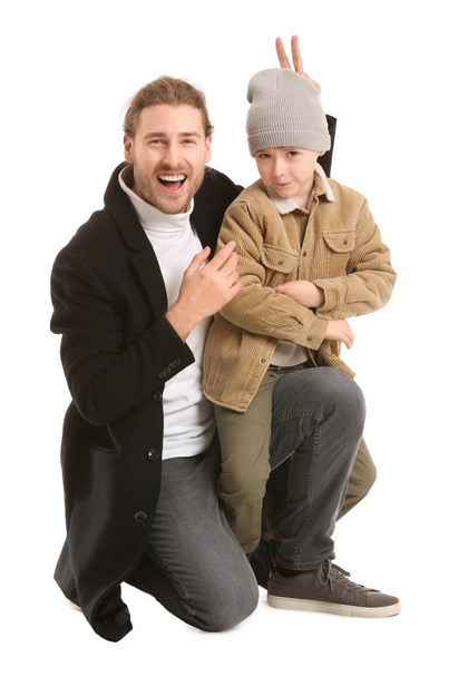 Όμορφος άντρας και ο γιος του με χειμωνιάτικα ρούχα σε λευκό φόντο. - Φωτογραφία, εικόνα