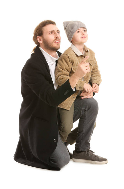 Όμορφος άντρας και ο γιος του με χειμωνιάτικα ρούχα σε λευκό φόντο. - Φωτογραφία, εικόνα