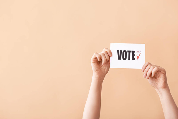 Mãos segurando papel com texto VOTE no fundo da cor
 - Foto, Imagem