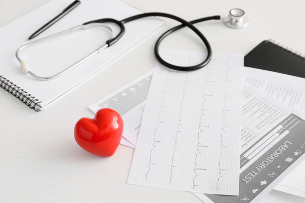 Estetoscopio, cardiograma, examen de laboratorio y corazón en la mesa del médico. Concepto de cardiología
 - Foto, imagen