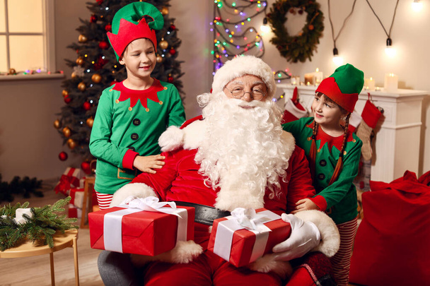 Święty Mikołaj i małe elfy dzieci z prezentami w pokoju urządzone na Boże Narodzenie - Zdjęcie, obraz